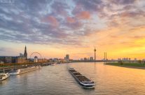 Die Düsseldorfer Skyline mit Schiff auf dem Rhein bei Sonnenuntergang